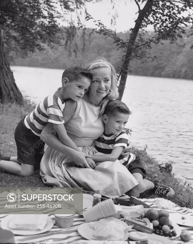 Mid adult woman picnicking with her two sons at a riverbank