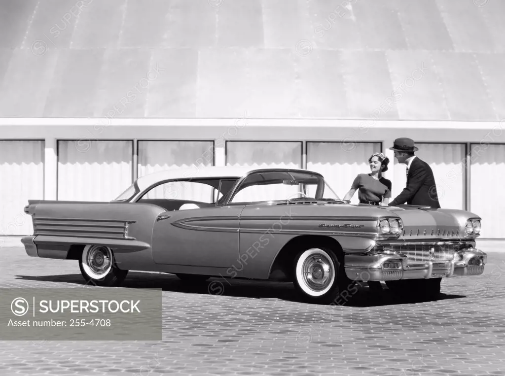 Man and woman standing behind a 1958 Oldsmobile Dynamic 88 Holiday Coupe