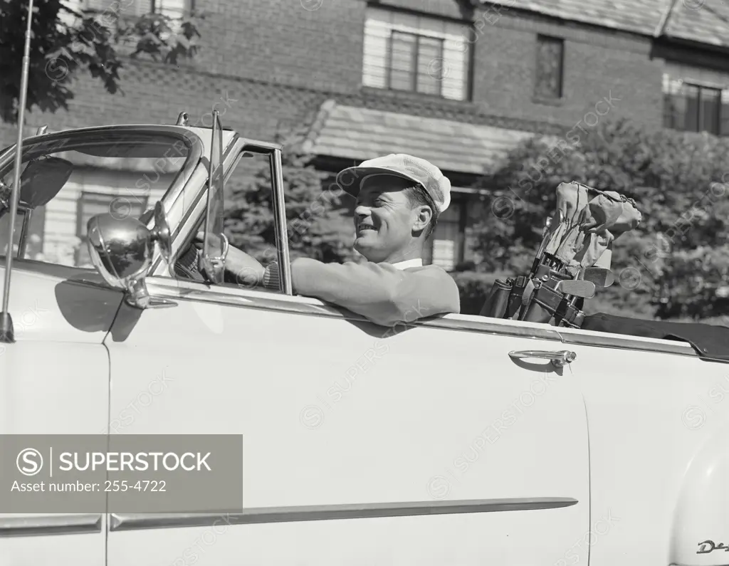 Vintage Photograph. Man in golf attire with clubs in back seat sitting in Chevrolet convertible