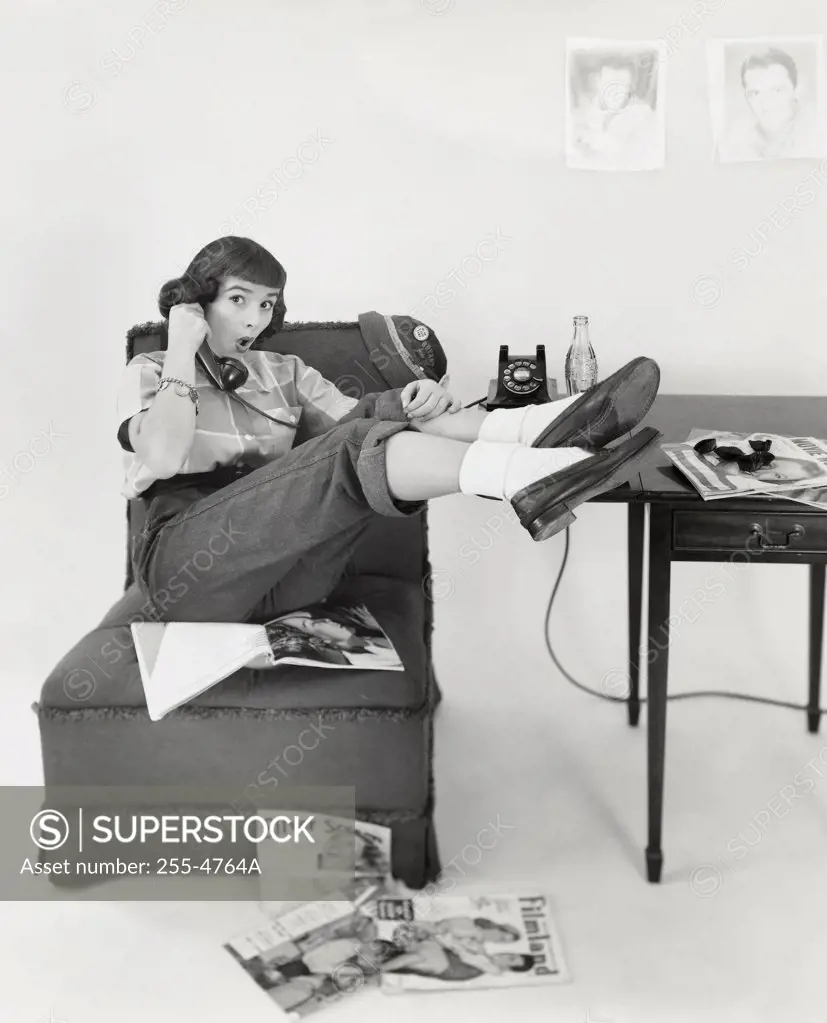 Teenage girl sitting on a chair and talking on the phone