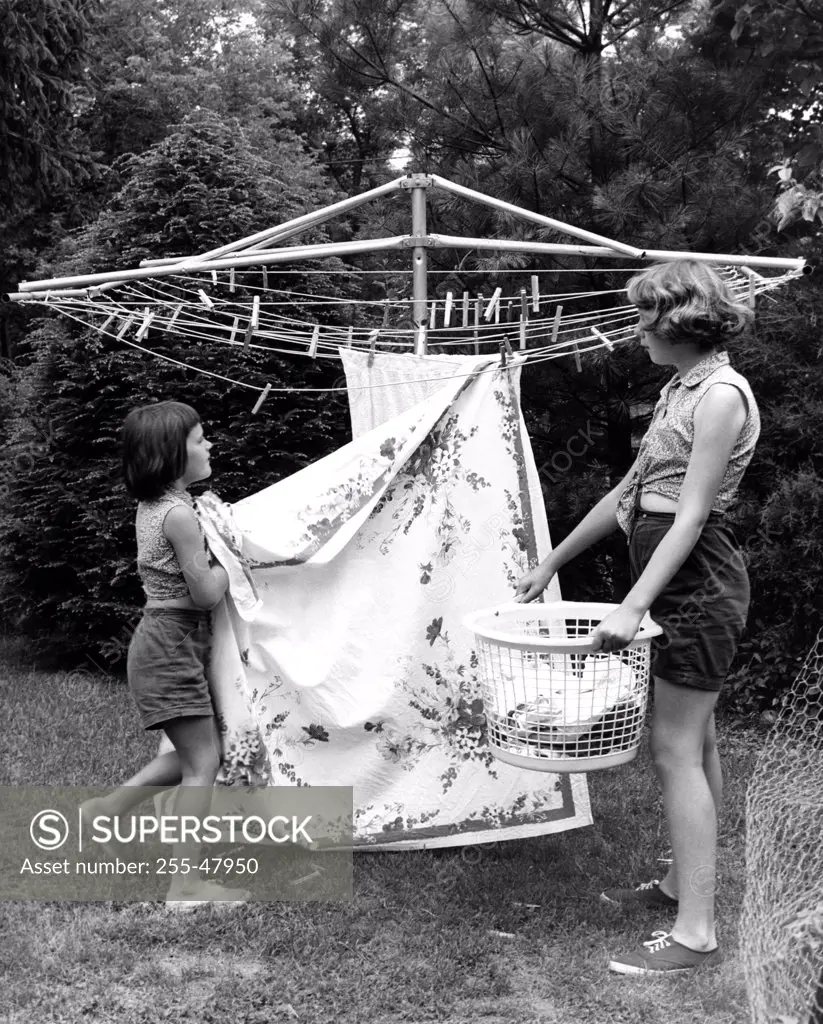 Mother and daughter hanging laundry in backyard