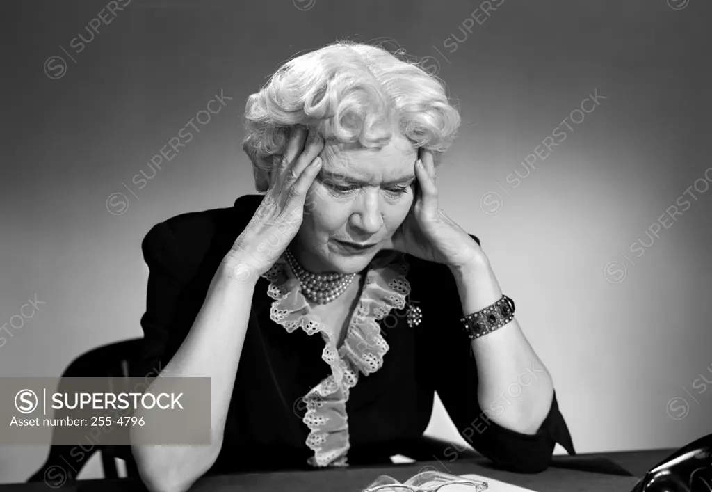 Senior woman sitting with head in hands
