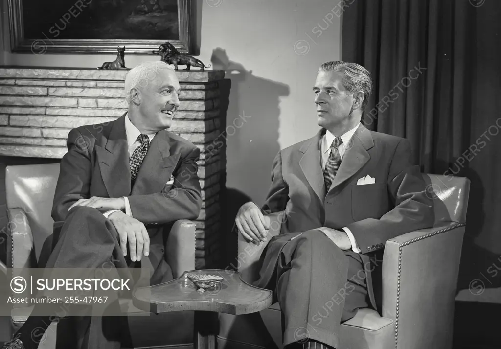 Vintage Photograph. Men in suits sitting in chairs talking with each other