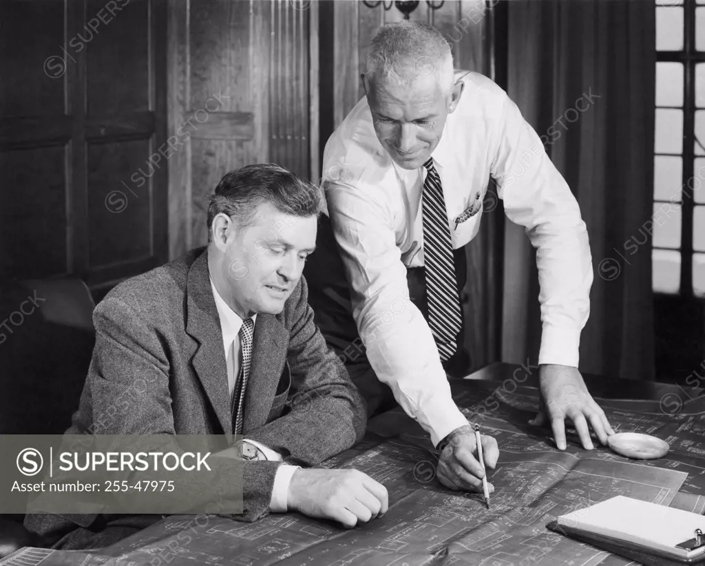 Two businessmen discussing blueprint in office