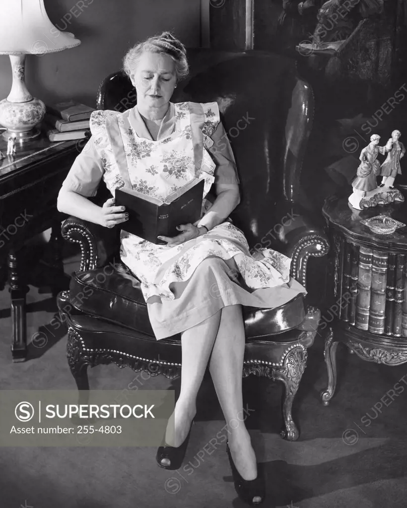 Vintage Photograph. Senior woman sitting in chair reading the Holy Bible