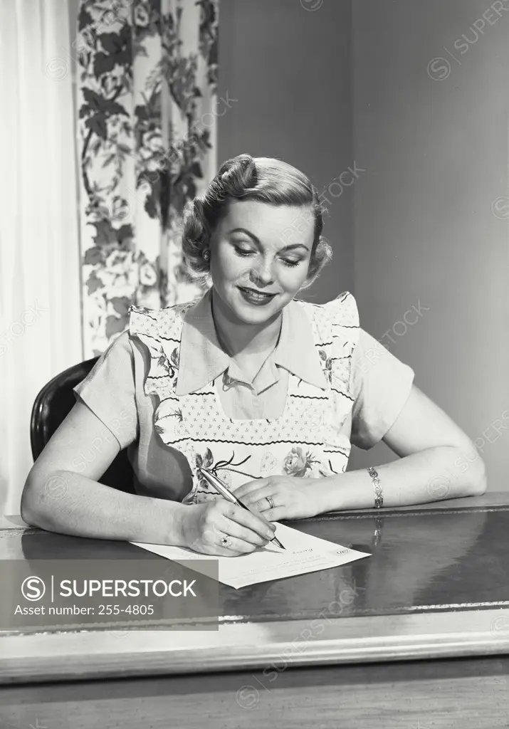 Vintage photograph. Woman in dress and apron writing paper