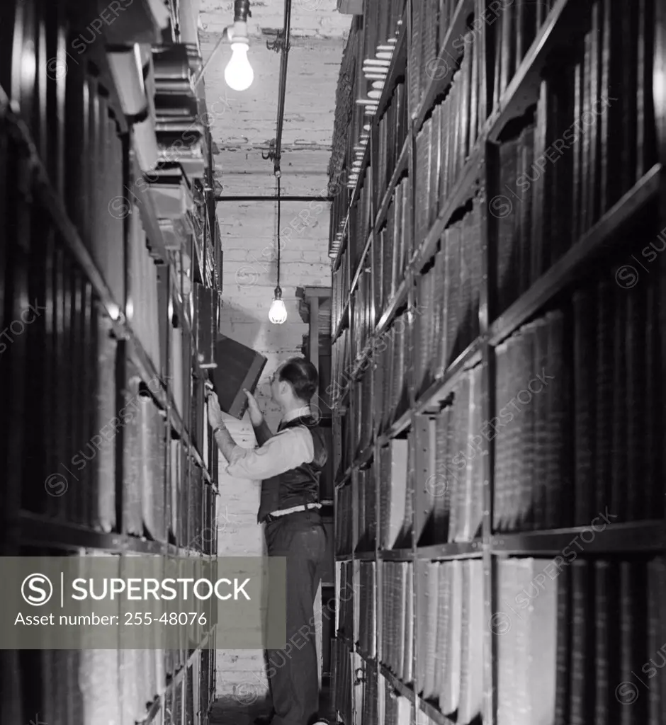Side profile of a businessman pulling a file from a shelf