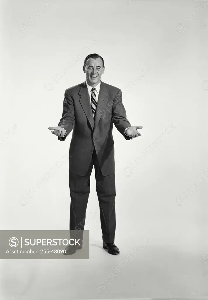 Vintage Photograph. Man in suit and tie standing on white background with arms open. Frame 1