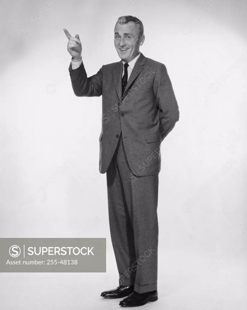 Studio portrait of businessman pointing upwards