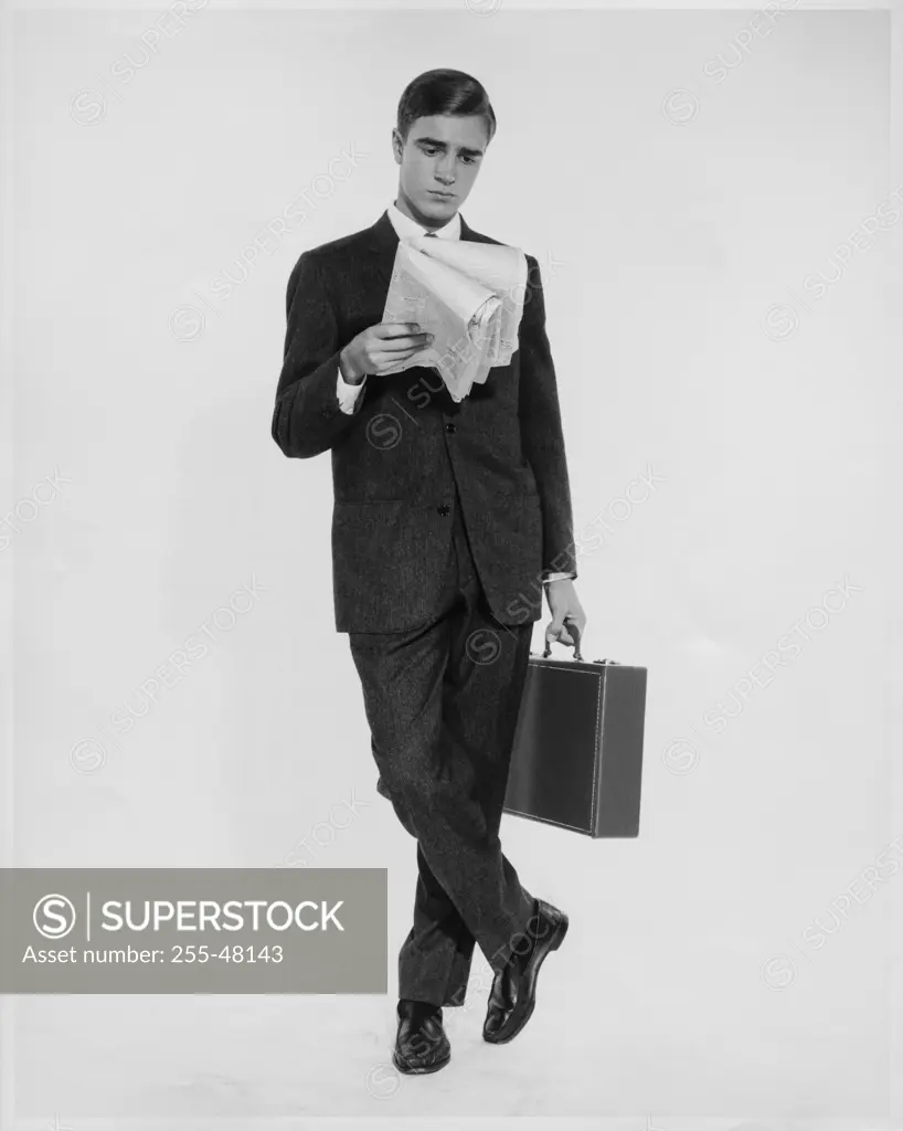 Businessman reading a newspaper and holding a briefcase