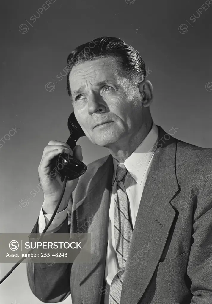 Vintage Photograph. Businessman listening to telephone receiver held up to ear