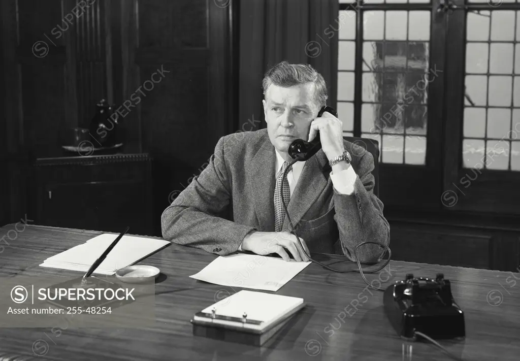 Vintage Photograph. Man in suit sitting at desk talking on telephone. Frame 3