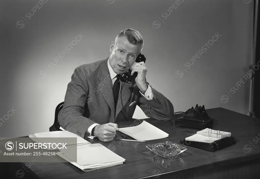 Vintage Photograph. Man in suit and tie sitting at desk and talking on phone. Frame 4