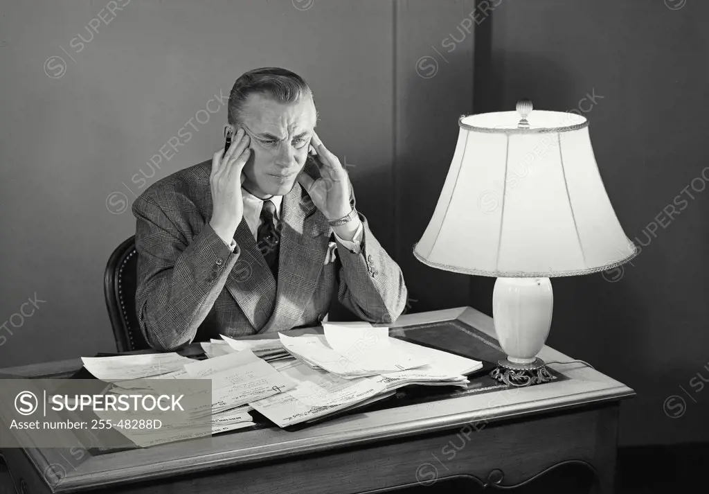 Vintage photograph. Businessman sitting at desk frustrated.