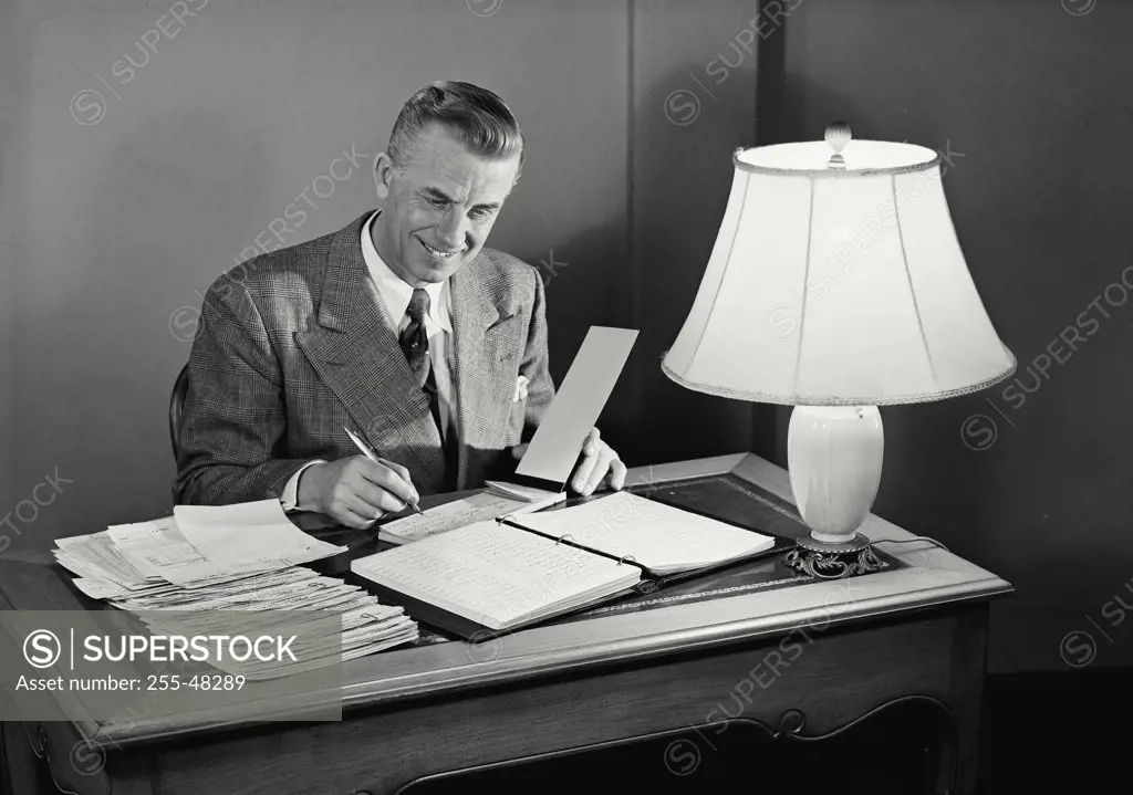 Vintage photograph. Businessman smiling working at desk.