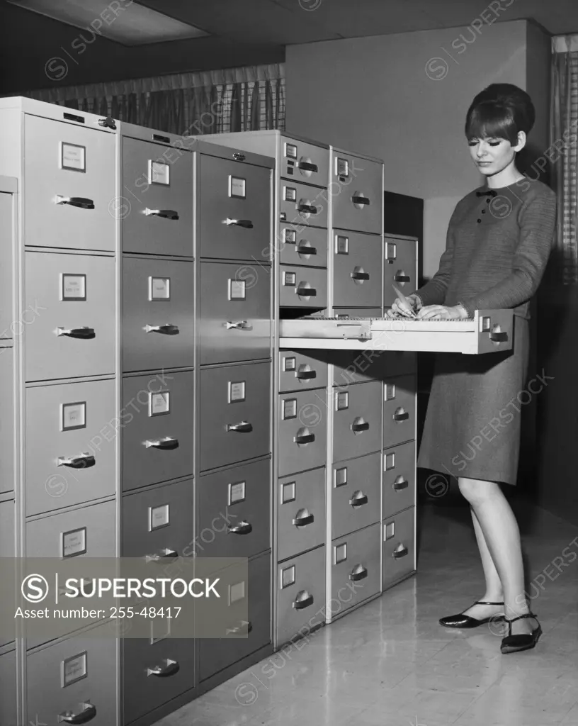 Businesswoman searching for files in filing cabinet