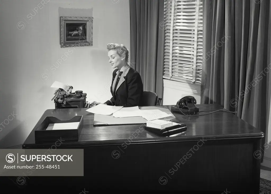 Vintage Photograph. Woman behind desk typing at typewriter
