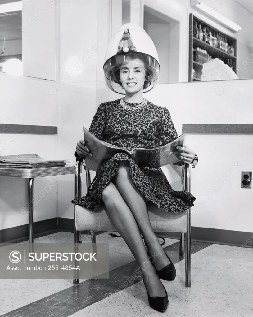 Portrait of a young woman sitting in an armchair under a hair dryer, 1964