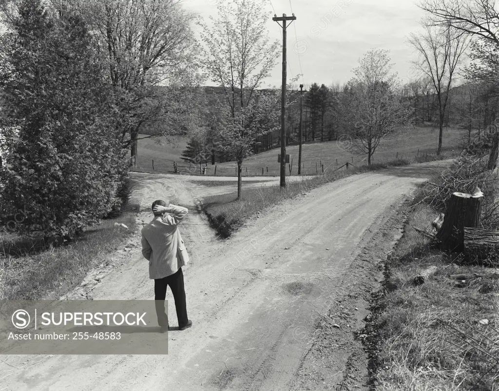 Vintage Photograph. Man standing at split in road. Frame 1