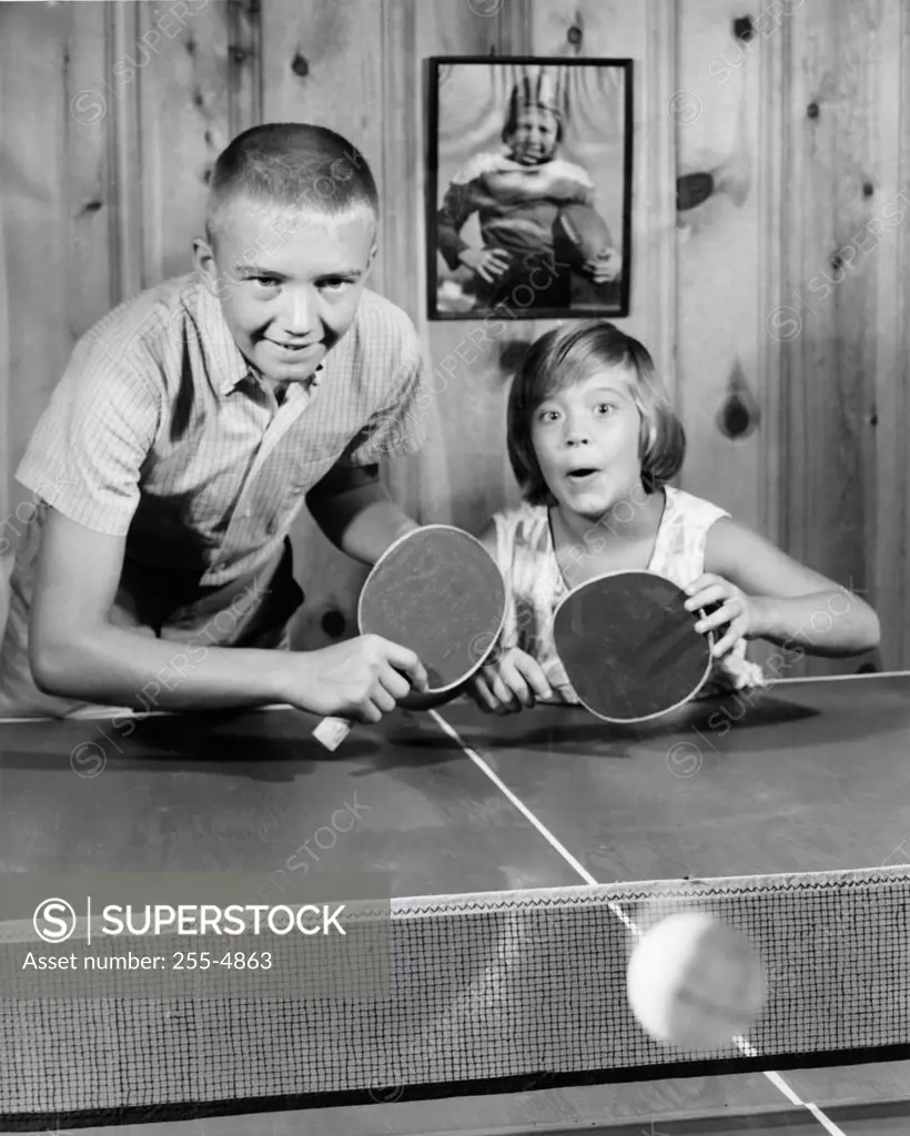 Boy and girl playing doubles table tennis