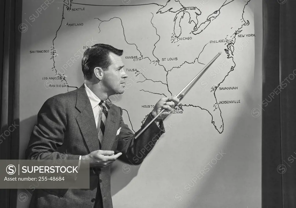 Vintage photograph. Businessman pointing with a pointer stick on the map of USA during a presentation