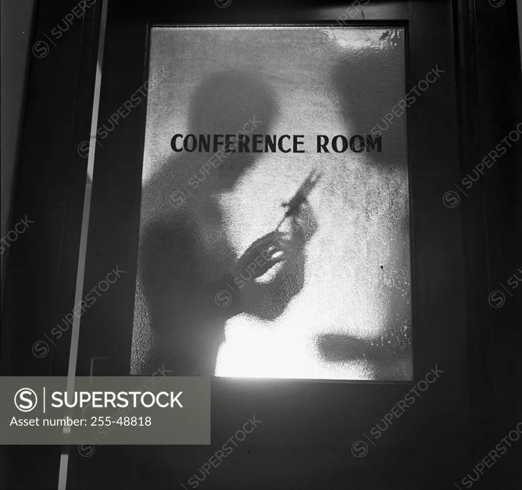 Vintage photograph. Silhouettes of physician with injection needle and patient in front of door marked "Conference Room"