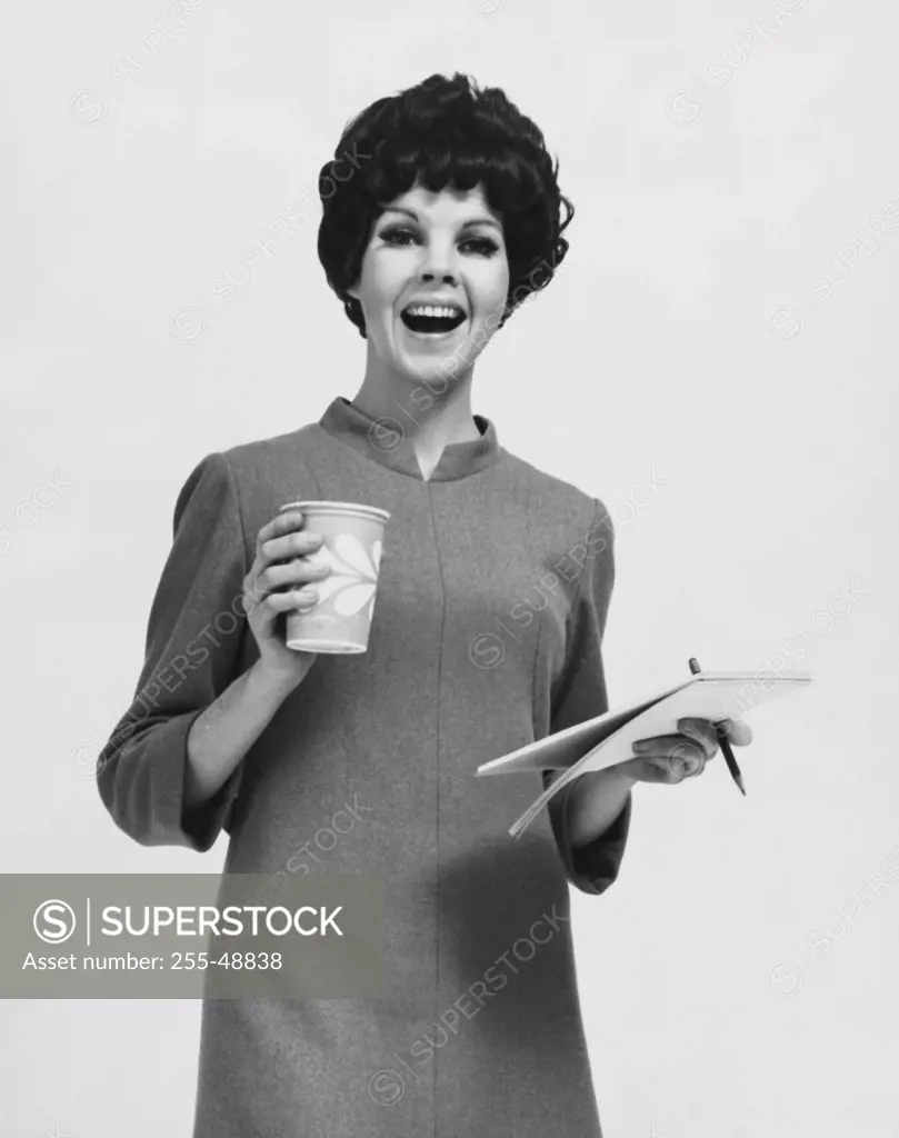 Businesswoman holding a note pad and a disposable cup