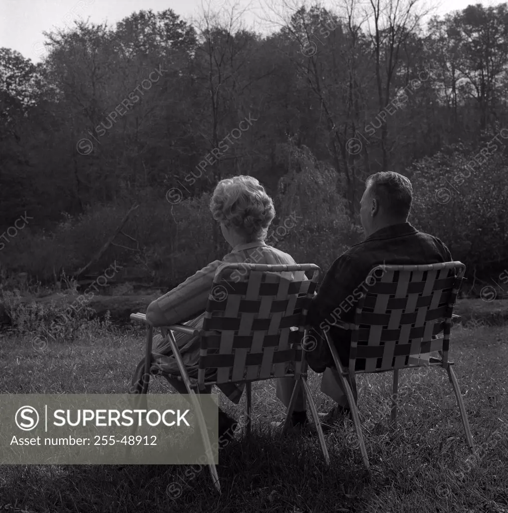 Couple sitting on chairs in backyard