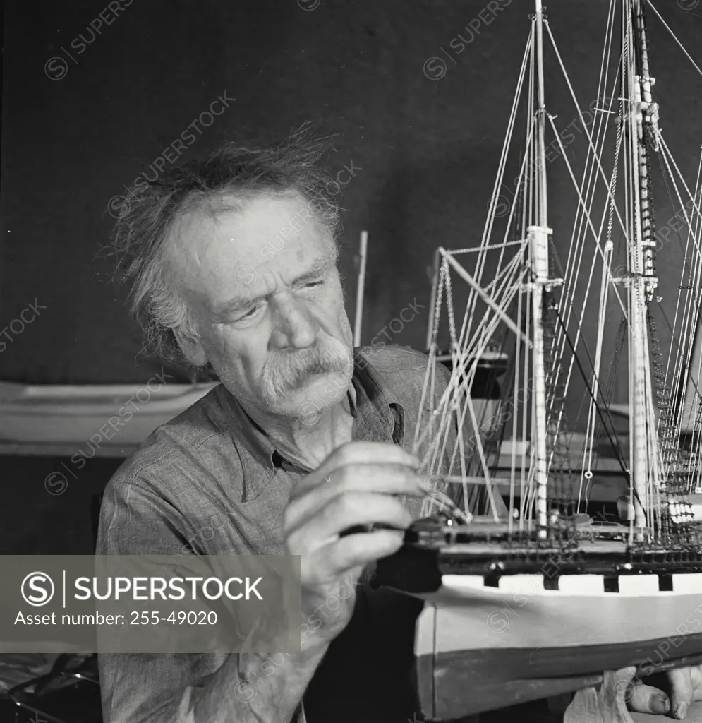 Vintage Photograph. Senior man making a model of a sailing ship