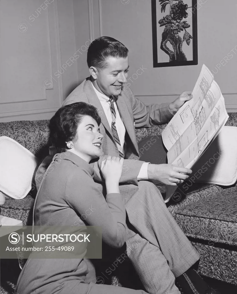 Mid adult couple looking at a blueprint and smiling