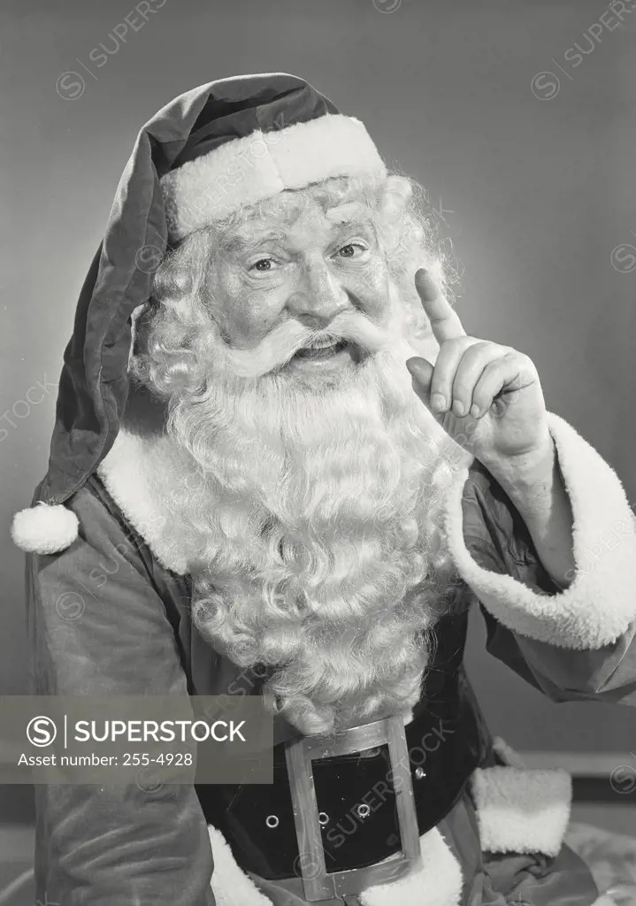 Vintage photograph. Close-up of man in Santa Claus costume smiling with hand raised pointing finger