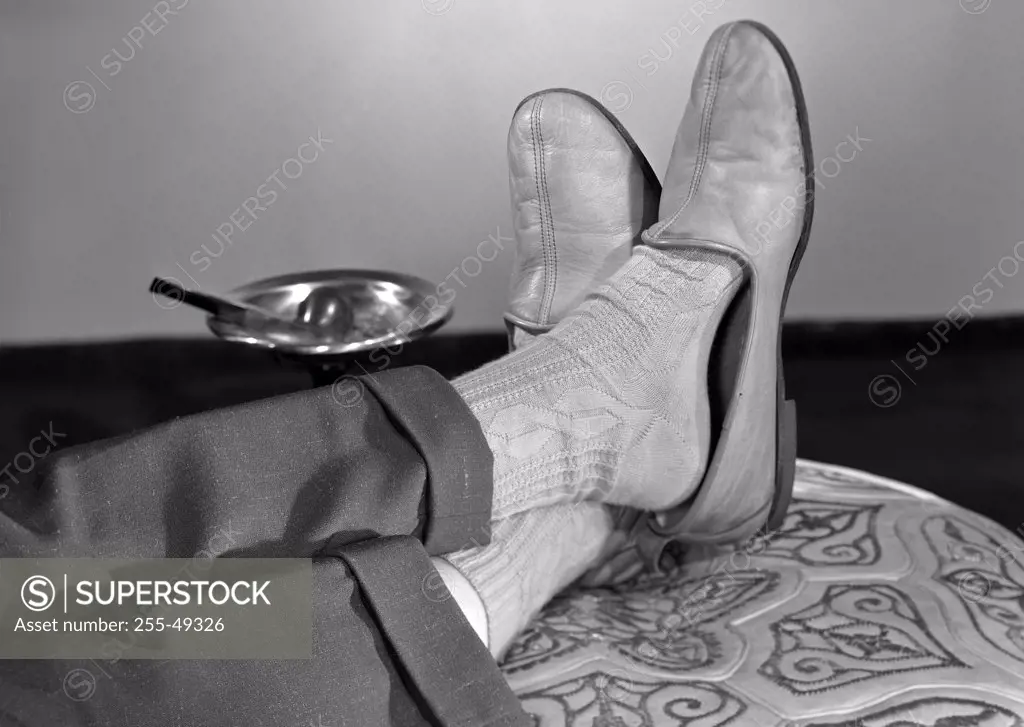 Low section of man relaxing with legs crossed at ankles