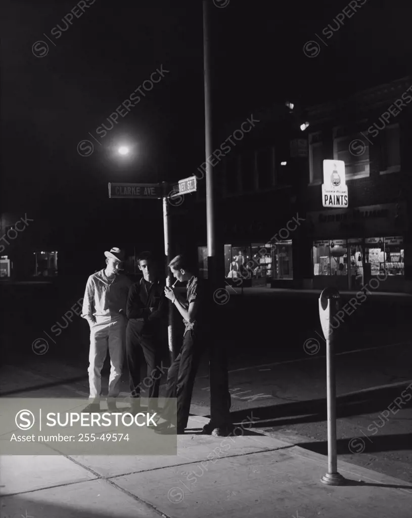 Three teenage boys standing on the sidewalk