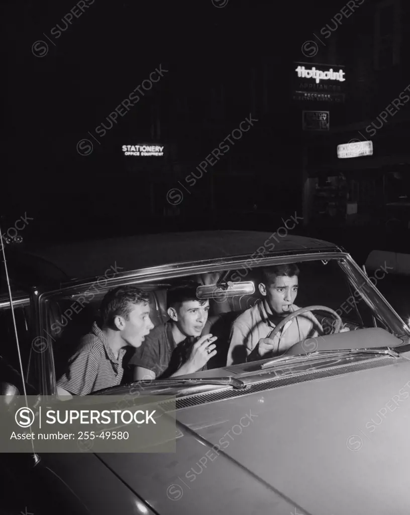 Three teenage boys looking shocked in a car