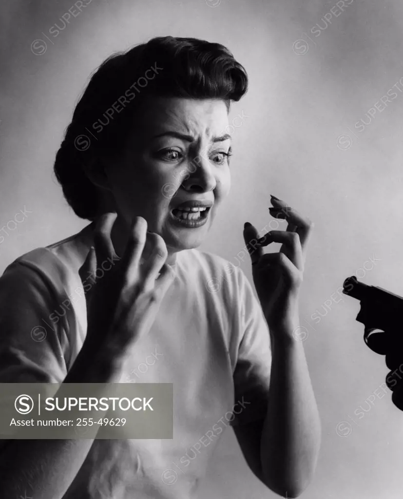 Studio shot of woman being threatened with gun