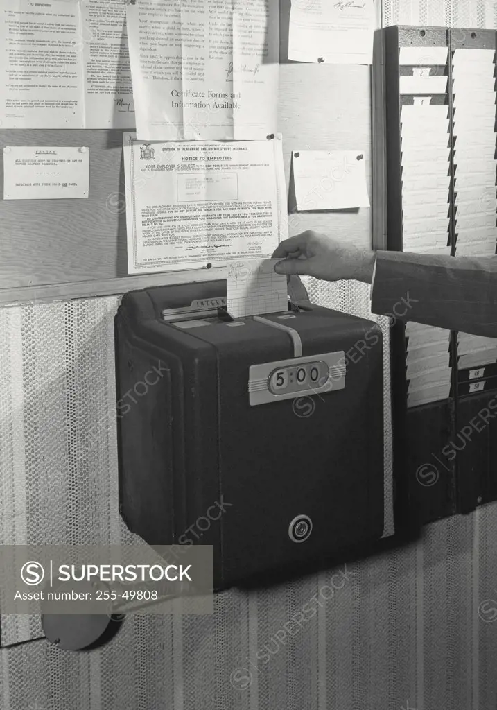 Vintage photograph. Close-up of a person's hand inserting time card in a time clock