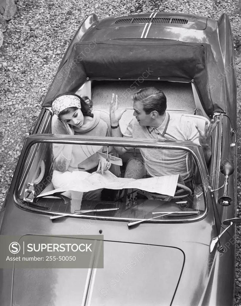 High angle view of a young couple sitting in a car and reading a map