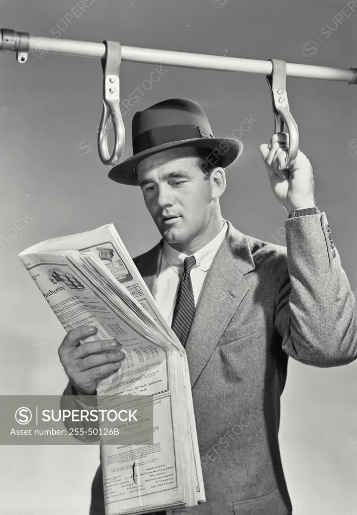 Vintage Photograph. Man in suit and hat on bus reading newspaper