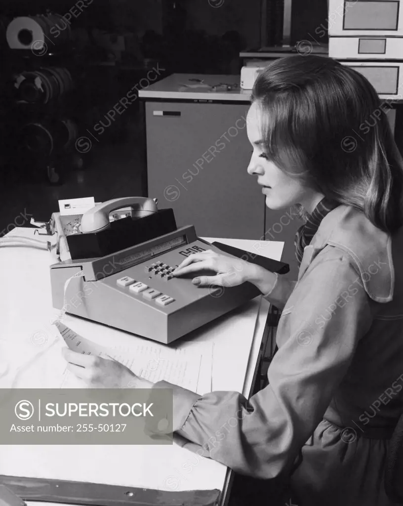 Side profile of a businesswoman using telecommunications equipment in an office