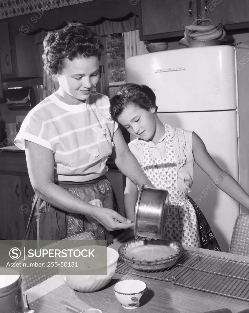 Mid adult woman preparing food with her daughter standing beside her