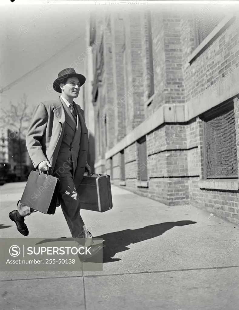 Vintage photograph. Businessman in suit with briefcase walking on sidewalk. 