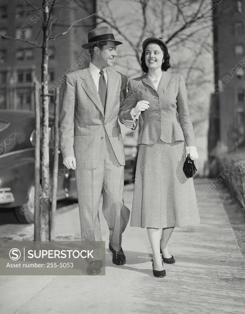 Vintage photograph. Smiling man and woman walking on city sidewalk