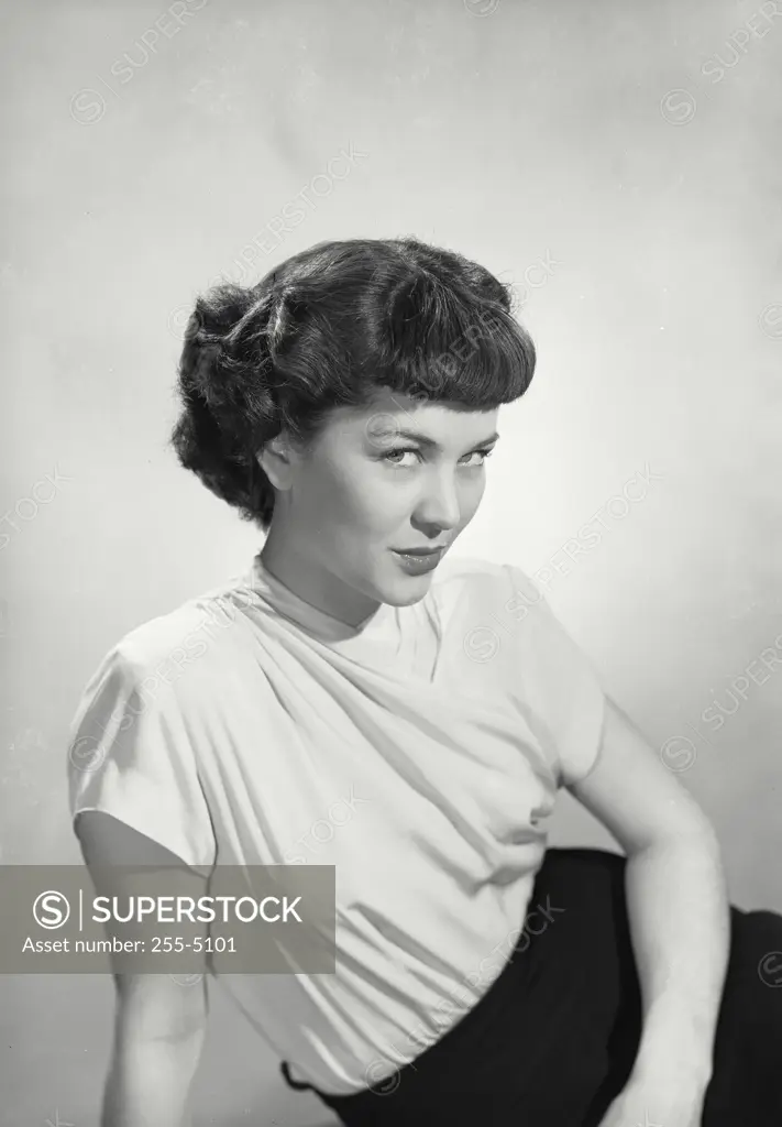 Vintage Photograph. Woman with short hair leaning on hand and looking up at camera.