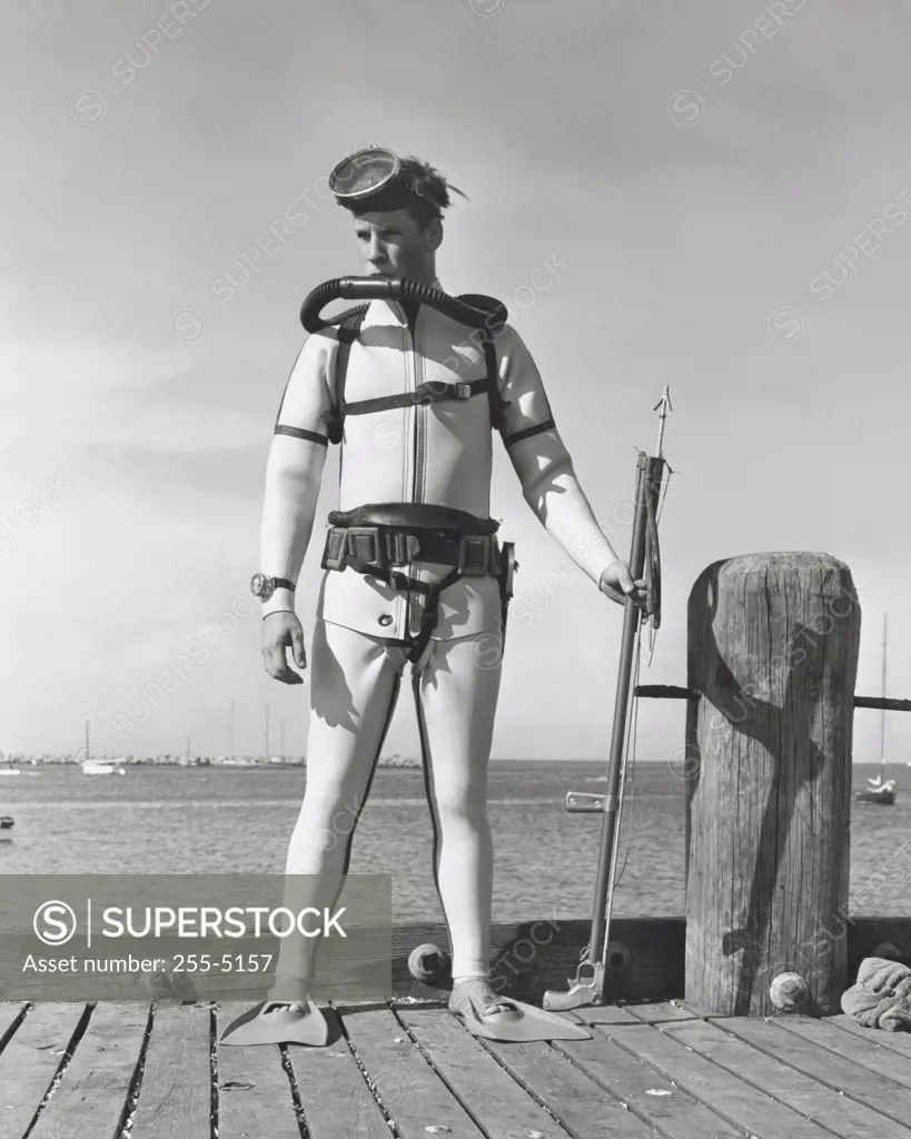 Scuba diver standing on pier and holding harpoon