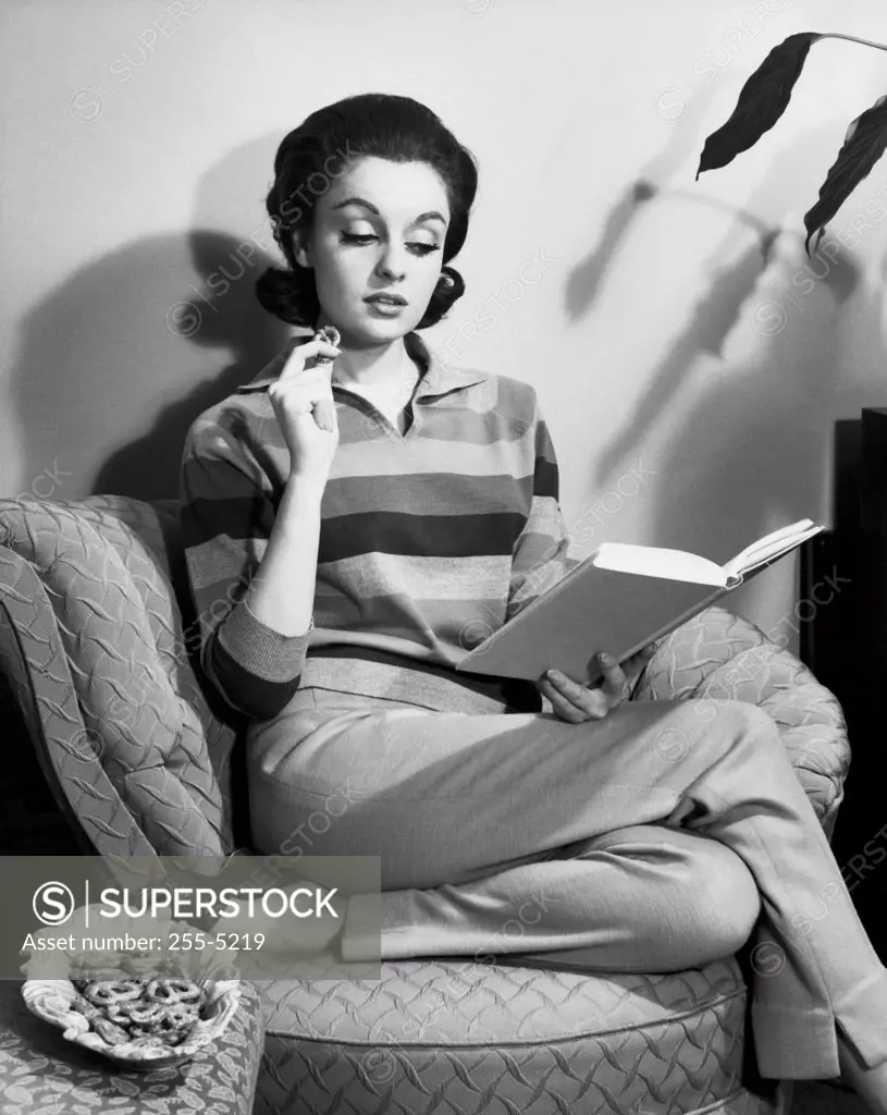 Young woman sitting on an armchair reading a book