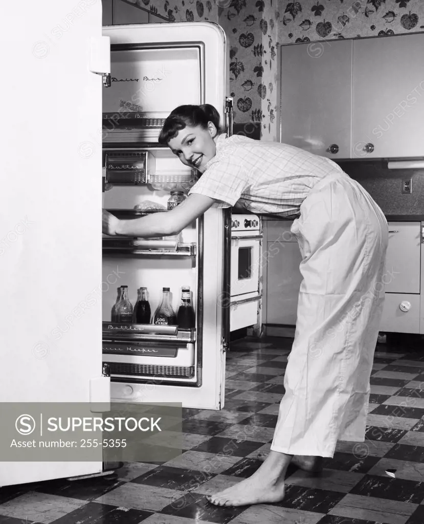 Side profile of a young woman standing in front of a refrigerator