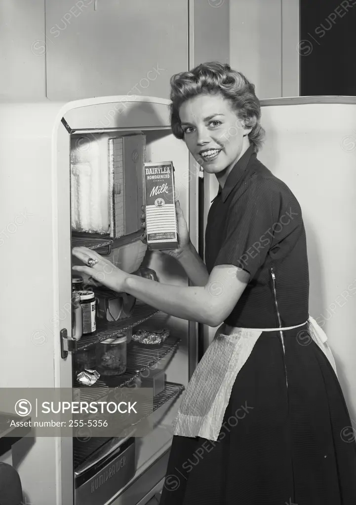 Vintage Photograph. Woman in apron looking in refrigerator. Frame 1