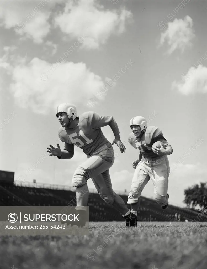 Vintage photograph. Football players running with football.