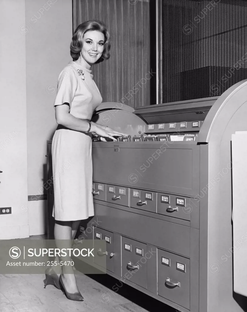 Portrait of a businesswoman standing beside a filing cabinet