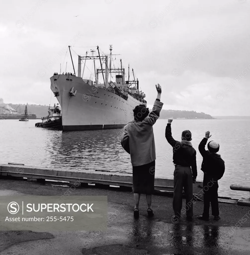 Mother with two children waving to departing steamship
